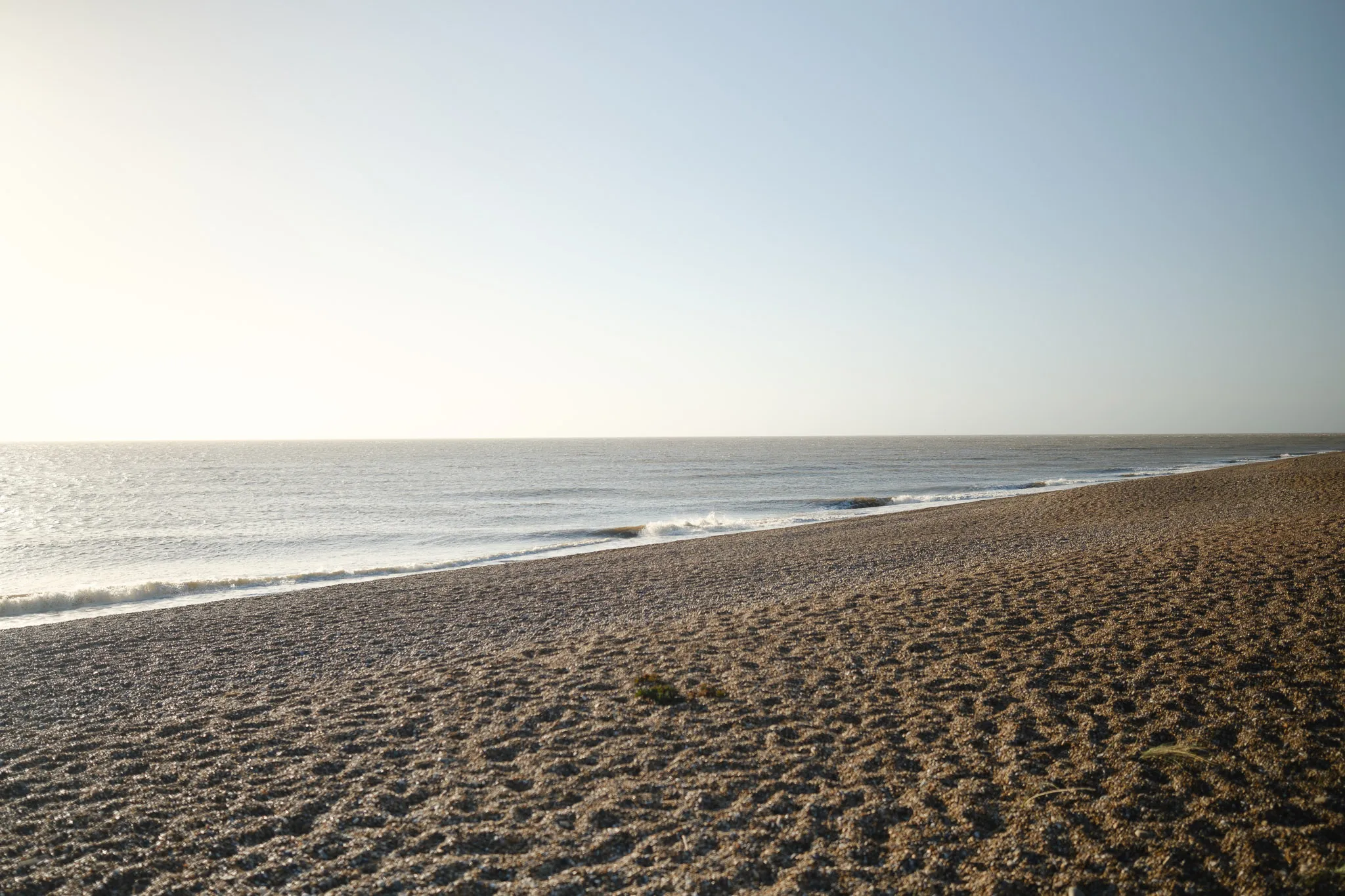 landscape view of a beach shoreline, with an overexposed (yet beautiful) blue/grey sky filling up the background.