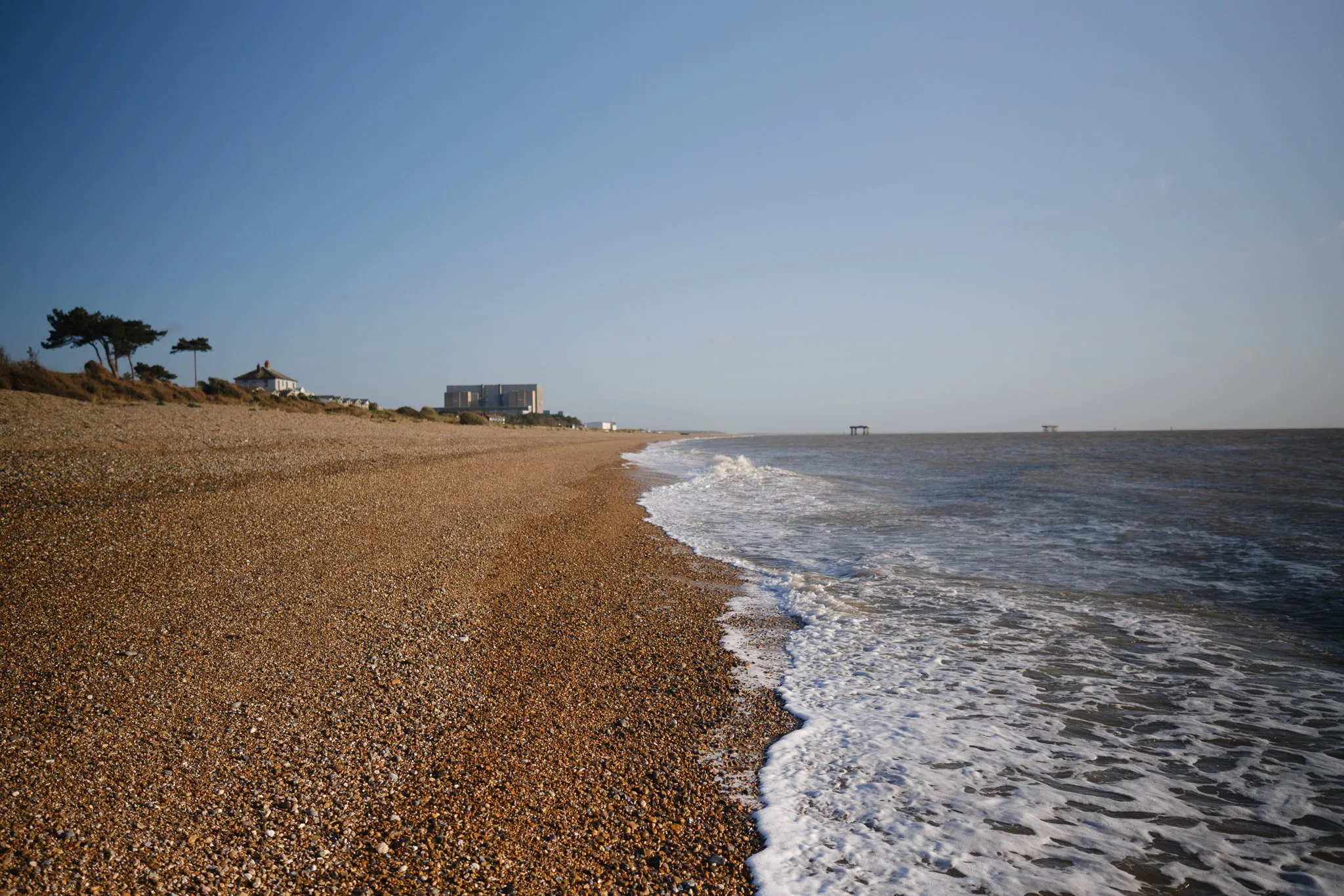 landscape, side view of a beach shoreline, filled pebbles and the tide just coming in... or going out.